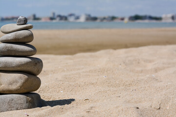 Fototapeta na wymiar Stack of stones on beautiful sandy beach near sea, space for text