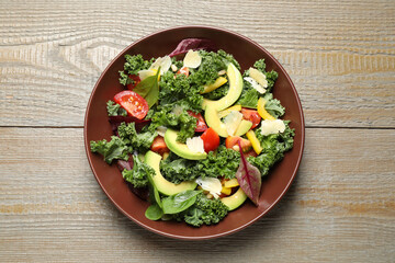 Tasty fresh kale salad on wooden table, top view