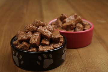 Wet pet food in feeding bowls on wooden background