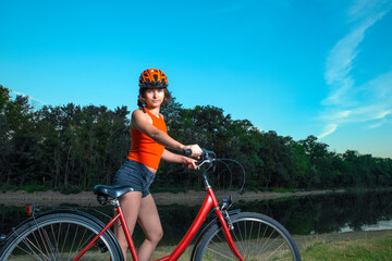 Fototapeta premium girl cyclist in a helmet in the morning along the river