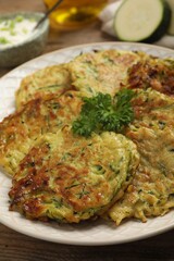 Delicious zucchini fritters served on wooden table, closeup