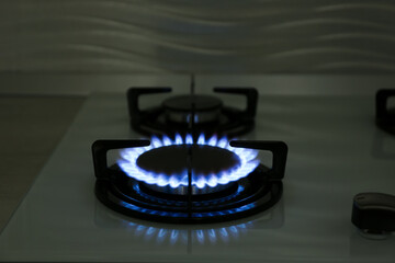 Modern gas cooktop with burning blue flame in kitchen at night