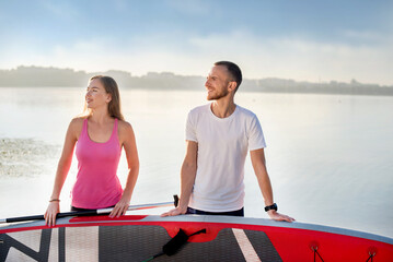 Attractive couple standing with sup board, concept of active life