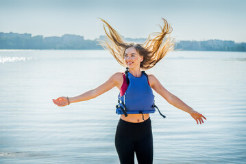 Happy woman in life jacket jumping for joy, blows out the hair. Concept of freedom, happiness