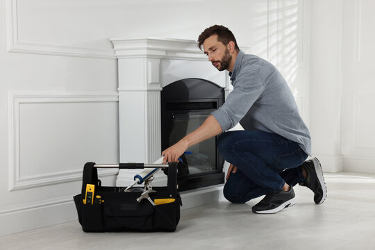 Man installing electric fireplace near white wall in room