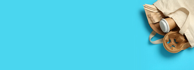 Paper and wooden tableware in cotton bag on turquoise background, top view with space for text. Banner design