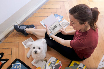 woman sitting with her little dog looks at the scrapbooks