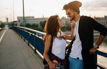 Portrait of happy couple having fun while driving a long board in city. People skateboard concept