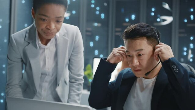 Asian man of tech specialists communicating with african amercan woman at server room. Professional IT service managers developing software. Call center