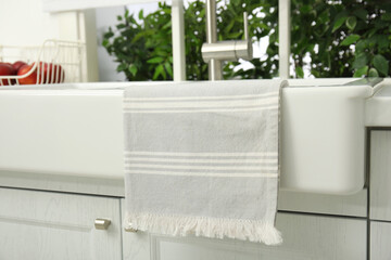 Clean towel hanging on white sink in kitchen