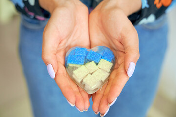 Women's hands hold a toy heart. The color is yellow and blue of the Ukrainian flag.
