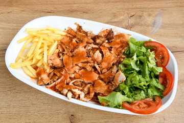 Turkish and Arabic Traditional Ramadan doner kebab with tasty tomato sauce and rice or turkish pilav in white plate on wood table background. ( Pilav ustu doner)