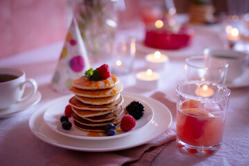 Pancakes in a plate decorated with berries and poured with sauce, birthday serving, selective focus