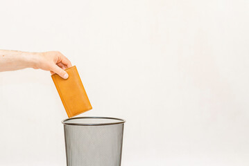 The orange wallet is thrown into the trash,can for disposal and recycling.White,gray background,selective focus,copy space.