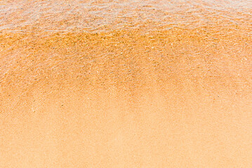 Soft beautiful sea wave on sandy beach. Water bright background.Top view.Copy space.