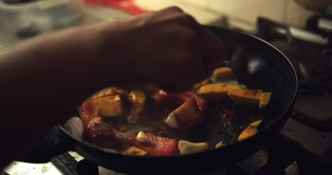 Mixing onion, tomato, chili and "zapallo loche" in a frying pan. Slow Motion 4k.