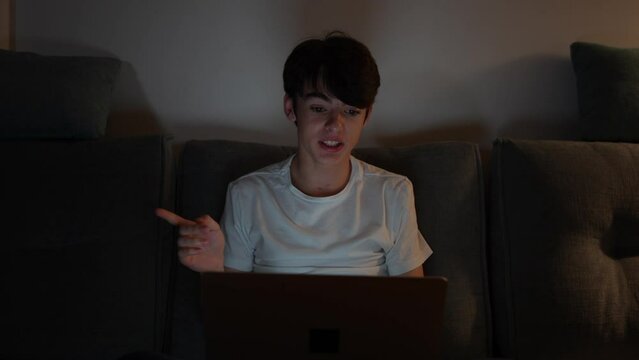 Teenager boy having a video conference on laptop at night