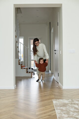 Fototapeta na wymiar Adorable kid holding mother's hands, little daughter walking down corridor. Happy childhood.