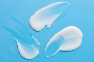 A sample of white moisturizer on a blue background. Cosmetic product for the skin.