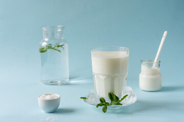 Obraz na płótnie Canvas Ayran or Doogh is a popular refreshing Middle Eastern beverage made with yogurt, water and salt. Blue background