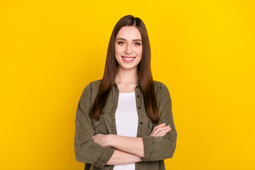 Portrait of young intelligent business lady with folded arms working in modern company isolated on yellow color background