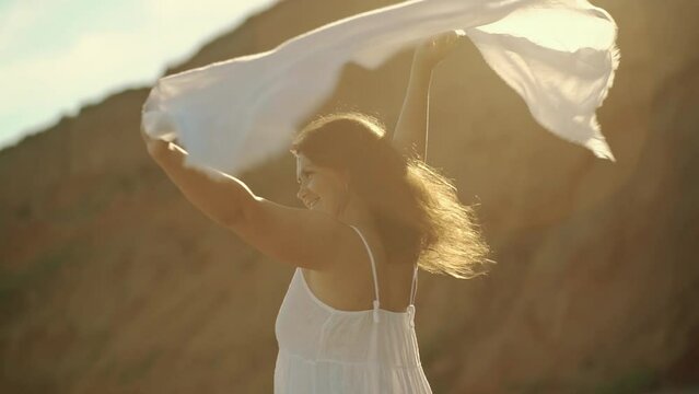Beautiful young woman girl holding pareo fabric in the wind overlooking the sea.
