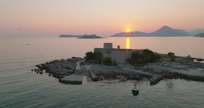orbit shot of Otocic Gospa island during sunset with sunset on background