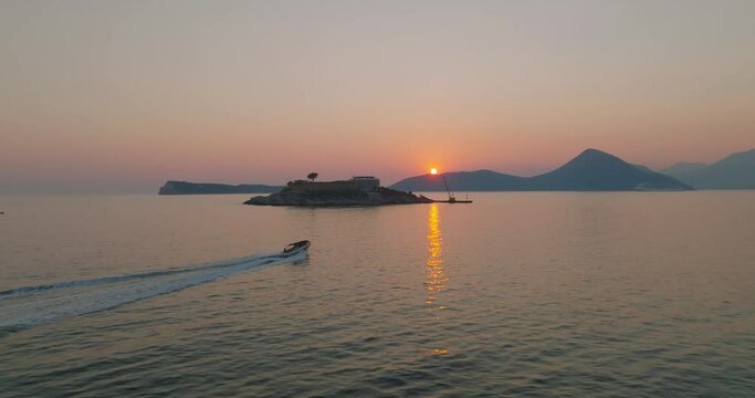 aerial view over the water of mamula island with speeding boat during sunset