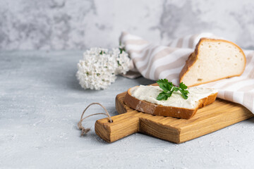 Cream cheese with herbs and seasoning on slice of fresh crunchy rye bread with cheese knife nearby