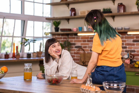 Very charismatic and good looking lesbian couple have a great time together in a large modern kitchen they discussing together and smiling large