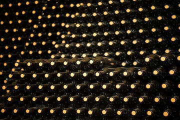 Many glass wine bottles on wine shelves. interior in distillery. Row of Stacked wine bottles in...