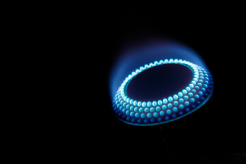 Gas burner with natural blue flame closeup on black background with copy space. Photo with long...