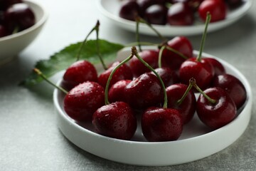 Fresh ripe cherries with water drops on light grey table, closeup