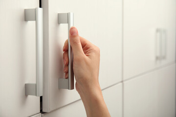 Woman opening cabinet door at home, closeup