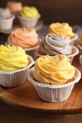 Tasty cupcakes with cream on wooden stand, closeup