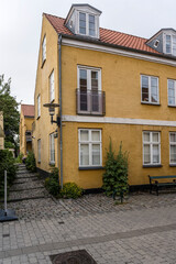 Fototapeta na wymiar traditional houses and Hollyock plants on cobbled pavement, Dragor, Denmark