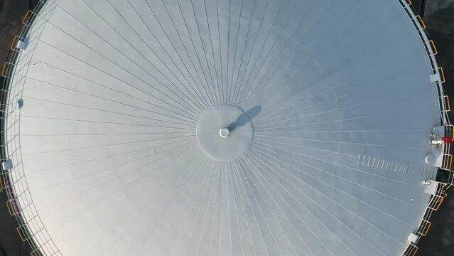 Oil storage tanks in rows in the factory. Drone aerial view. Oil storage tanks in the sunset time with light in the side, flying over the tanks.  Industry, business, economy concept b-roll footage.