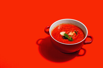 Spicy tomato soup. Healthy vegan hot dish, croutons, vintage cutlery. Bright red background