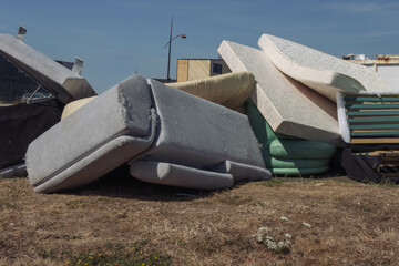 Dirty used mattresses and a sofa are dumped in a landfill.close up