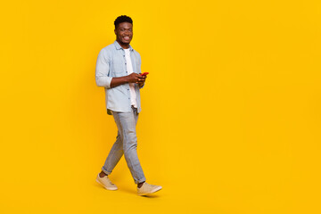 Fototapeta na wymiar Full size photo of millennial guy walk use smart device communicate blog followers isolated bright color background