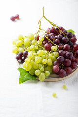 Red and yellow grape on the white linen tablecloth