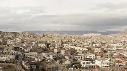 Fototapeta na wymiar Aerial view of old Cappadocia Park in Turkey. Action. Stone houses and buildings surrounded by rocks on cloudy sky background.