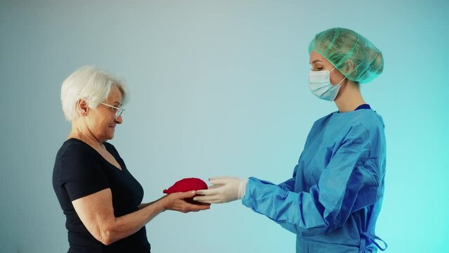 Conceptual shot of a surgeon giving heart transplant to an elderly lady - gift of new life from the donor to donee. High quality 4k footage
