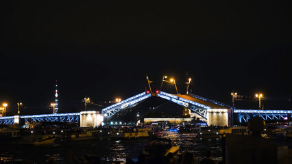 Fototapeta na wymiar Building bridges with boat traffic at night. Action. Beautiful bridge construction with lighting at night. Many boats on river are waiting for breeding of luminous bridge