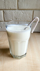 A glass of kefir on the table with a paper tube