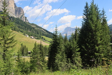Coravara, Italy-July 16, 2022: The italian Dolomites behind the small village of Corvara in summer days with beaitiful blue sky in the background. Green nature in the middle of the rocks. 