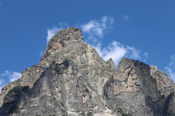 Fototapeta premium Coravara, Italy-July 16, 2022: The italian Dolomites behind the small village of Corvara in summer days with beaitiful blue sky in the background. Green nature in the middle of the rocks. 