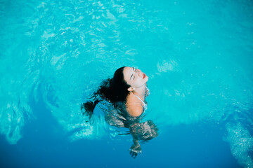 Girl emerging from blue water, copy space