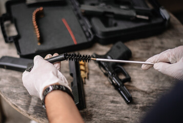 The gunsmith is sitting around cleaning the gun and disassembling and maintaining the pistol.