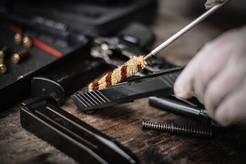 The gunsmith is sitting around cleaning the gun and disassembling and maintaining the pistol.